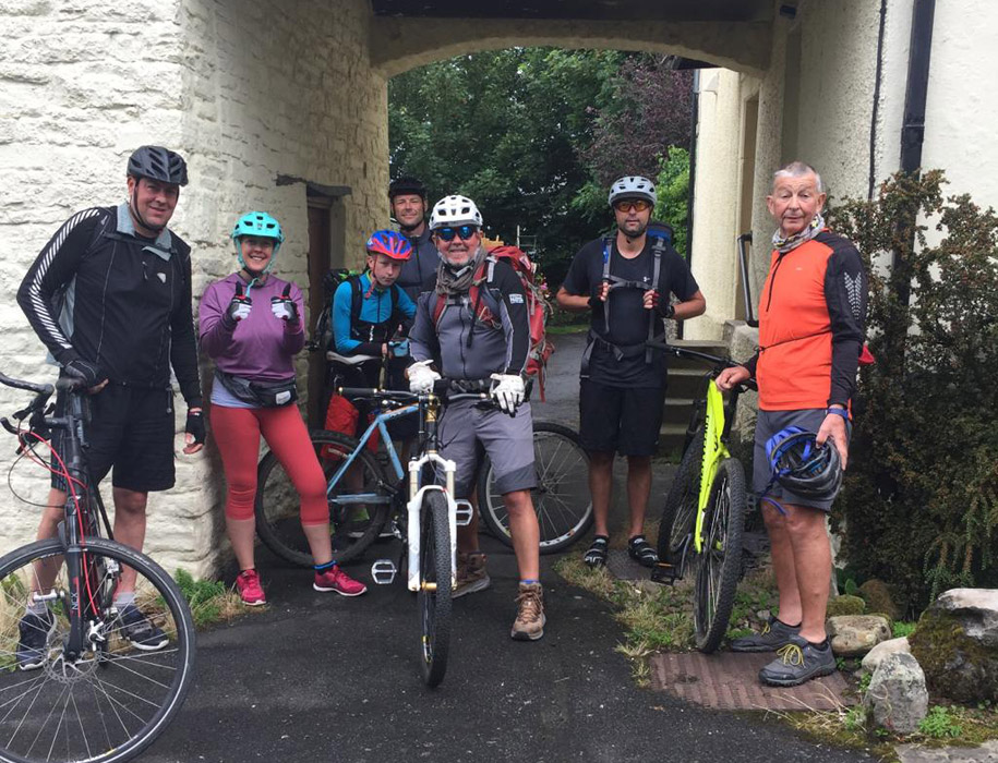 A multi-generational group of C2C cyclists stand with their bikes outside their Temple Croft B&B cycling accommodation in Alston before setting off on day two of their trip.